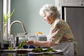 Anciana lavando las verduras en la cocina.
