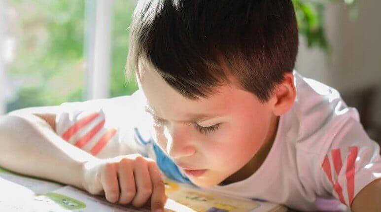 Niño con autismo leyendo un libro.