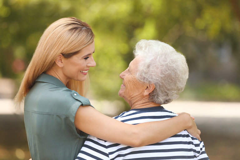 Foto de anciana con cuidadora felices de espaldas.