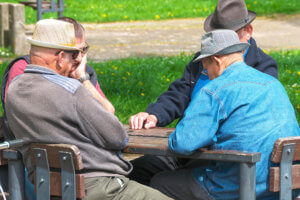 Grupo de ancianos sentados en sillas con una mesa en un parque.