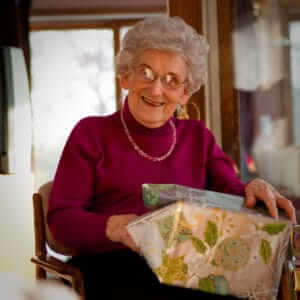 Fotografía de una anciana feliz abriendo su regalo por navidad.