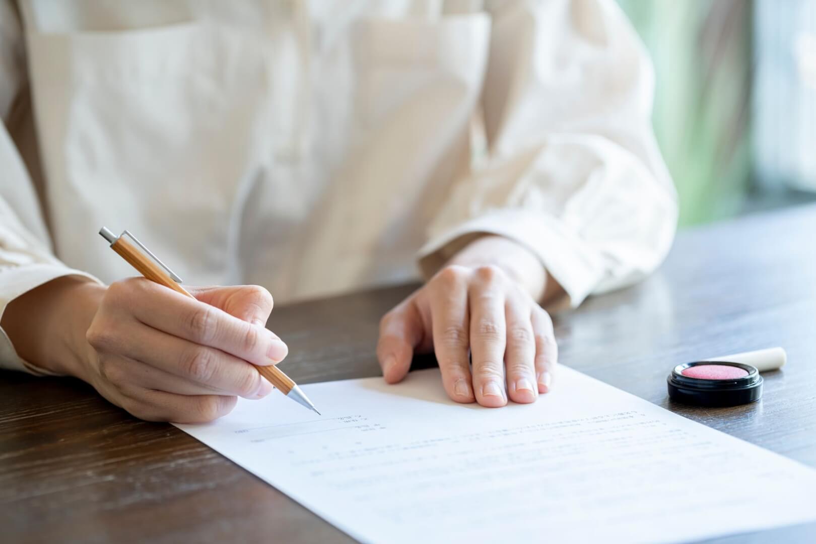 Un plano corto de una mujer firmando un documento de finiquito.