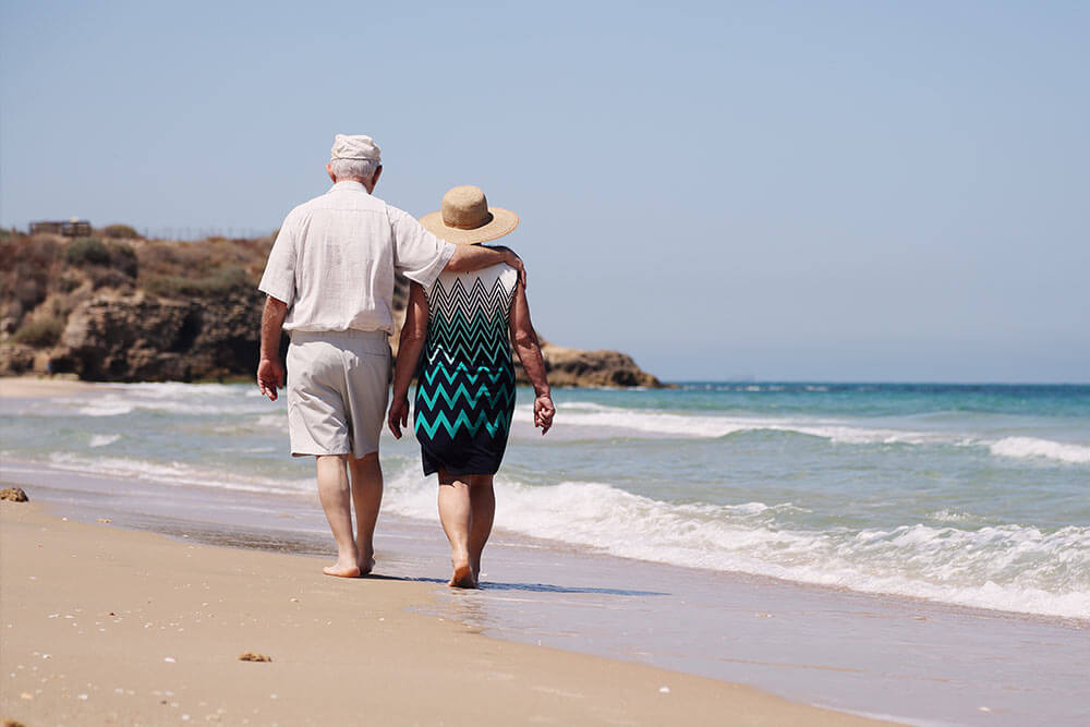 Pareja de ancianos pasea por la playa.