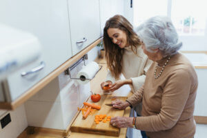 cuidadora y anciana cocinando