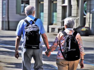Foto de una pareja de ancianos con mochila paseando por la calle.