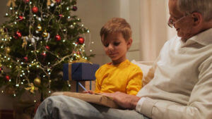 Abuelo con su nieto en el sofá celebrando la navidad.