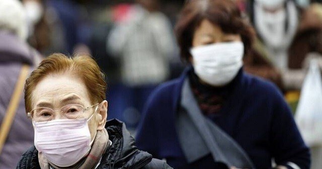 Dos mujeres asiáticas caminando por la calle ataviadas con una mascarilla.