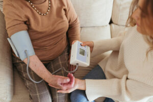 Cuidadora del hogar midiendo la tensión a anciana