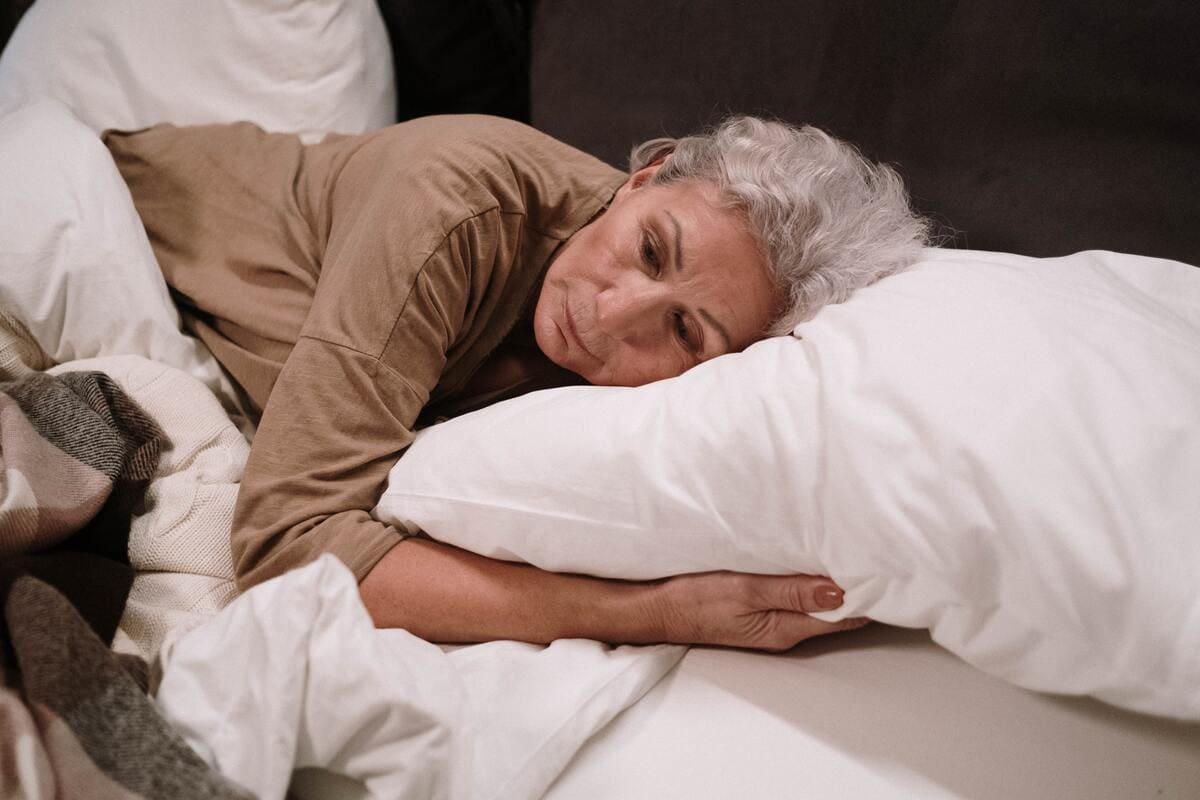 Una mujer mayor abrazada a una almohada.