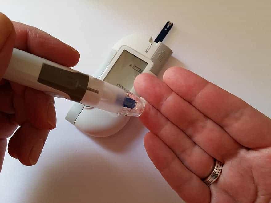 Medidor de diabetes y aguja pinchando dedo para sacar sangre para la prueba. 
