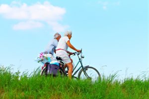Dos abuelos paseando en bicicleta alrededor de un paisaje verse