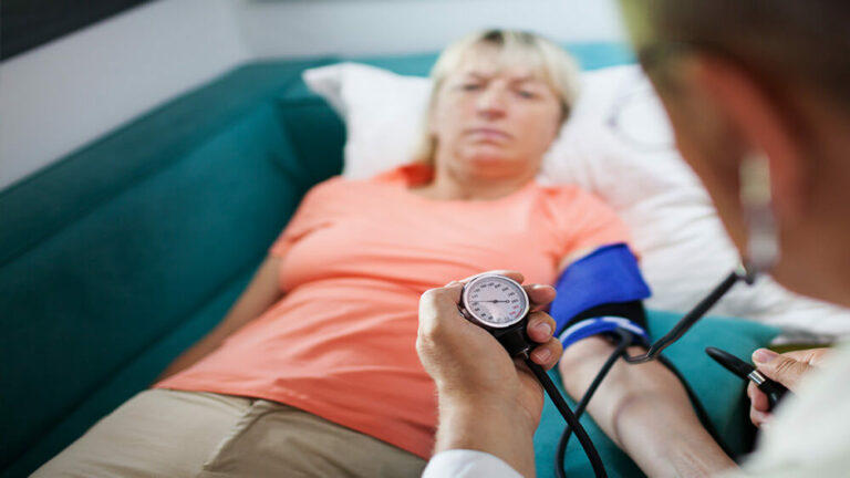 Médico revisando la tensión de una mujer.