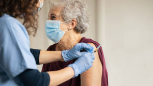 Cuidadora poniendo vacuna a anciana contra el Covid-29.