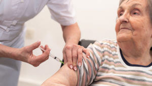 Enfermera pone una inyección a anciana.