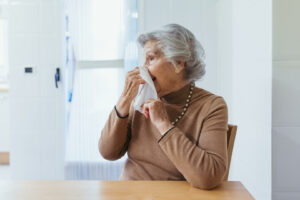 Anciana sonándose la nariz con un pañuelo de papel.