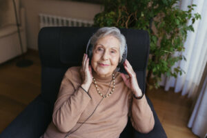 abuela escuchando música con unos cascos en su salón