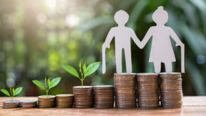 Pilas de monedas que van creciendo hasta llegar a la más alta donde se observa la figura de dos ancianos en papel.