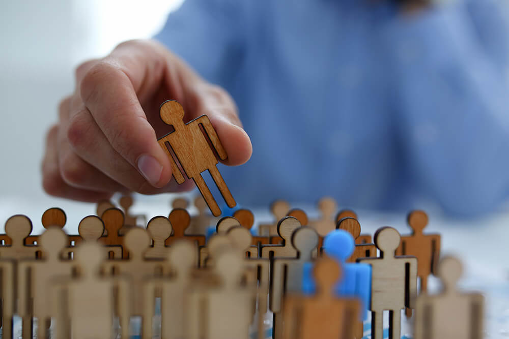 Un hombre coge una figura entre distintos muñecos de personas.
