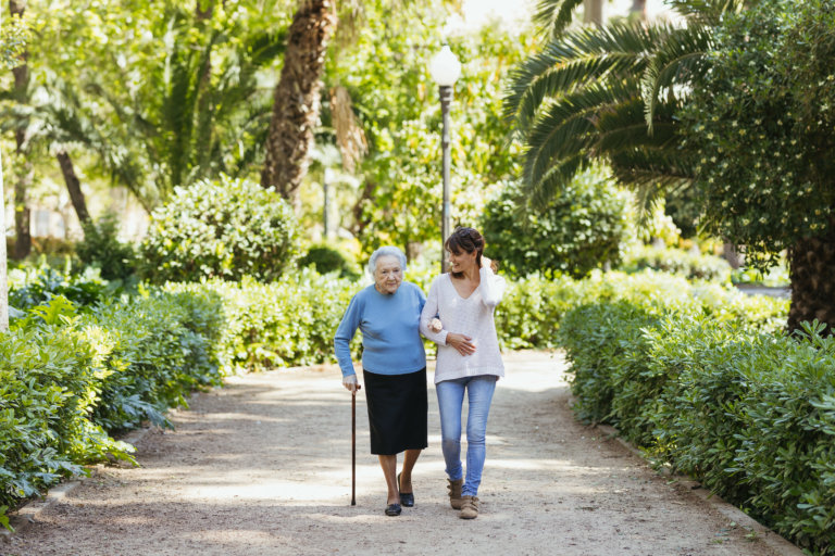 Abuela y cuidadora caminando por el parque ribalta