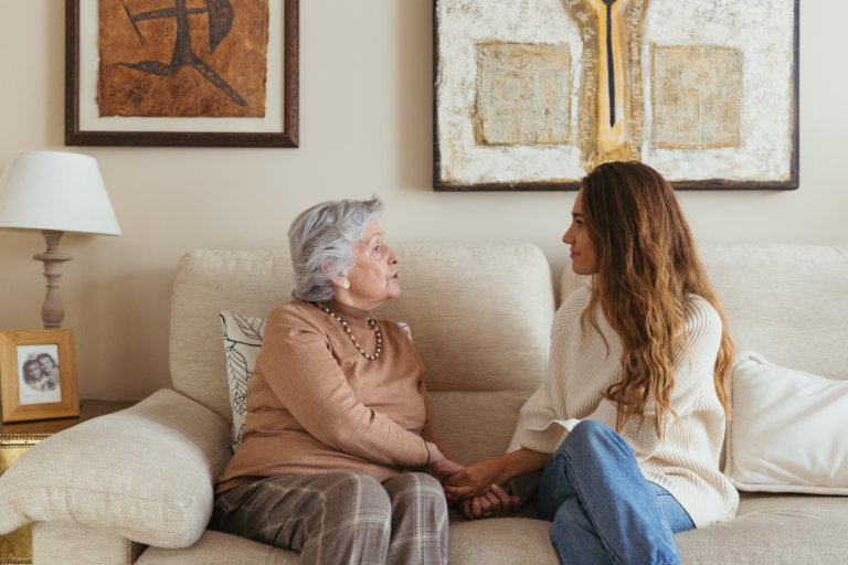 Abuela y cuidadora sentadas en el sofá