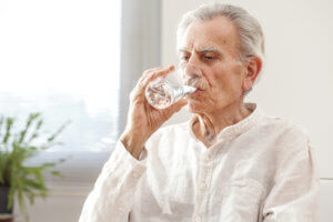 Anciano bebiendo un vaso de agua