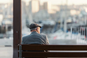 Anciano de espaldas sentado en un banco de la calle.