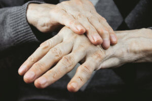 Manos de una anciana sujetando una a otra para que estas no tiemblen.