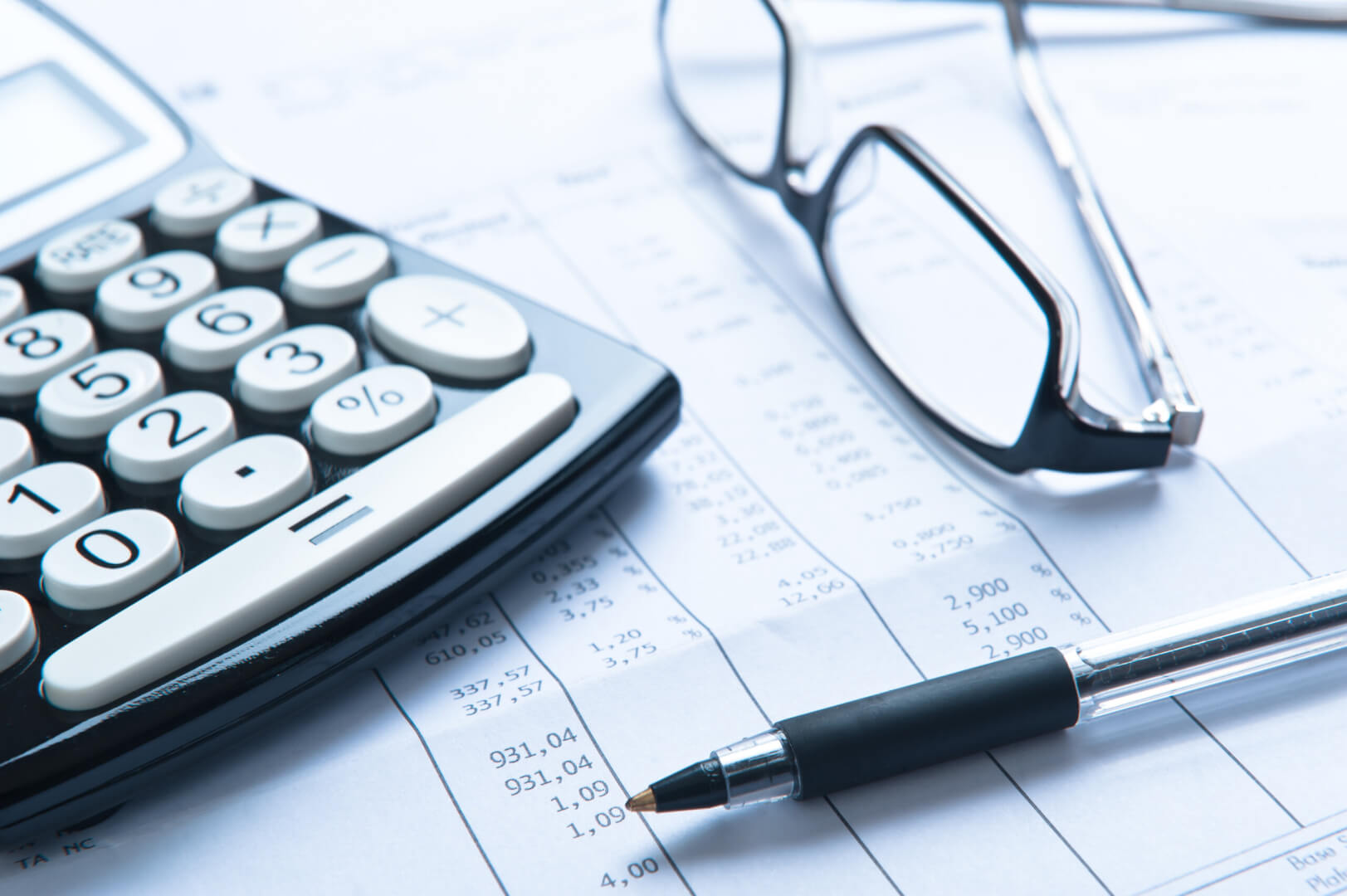 Una calculadora, unas gafas, un bolígrafo y un borrador de la declaración de la renta. 