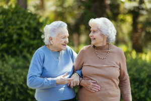 Dos señoras de la tercera edad pasean por el parque cogidas del brazo una de otra mientras hablan.