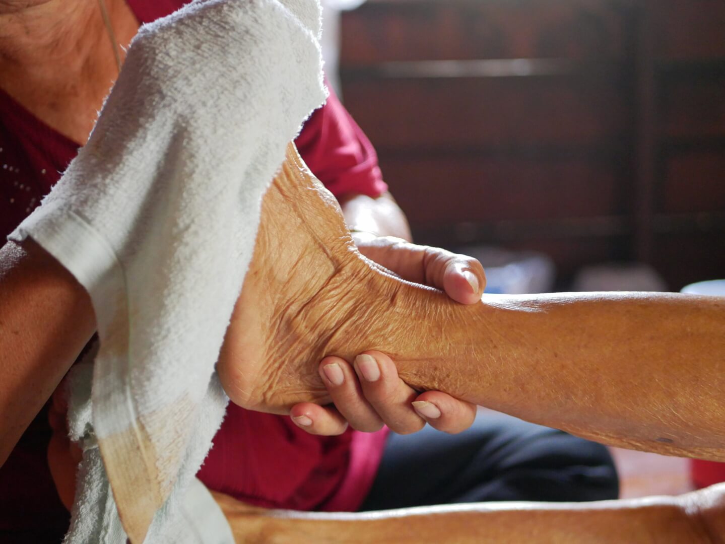 Un acompañante seca el pie de una persona mayor ante un posible caso de hipotermia.