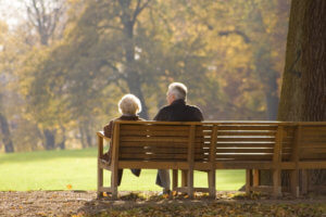 Pareja de ancianos respirando el aire otoñal sentados en un banco
