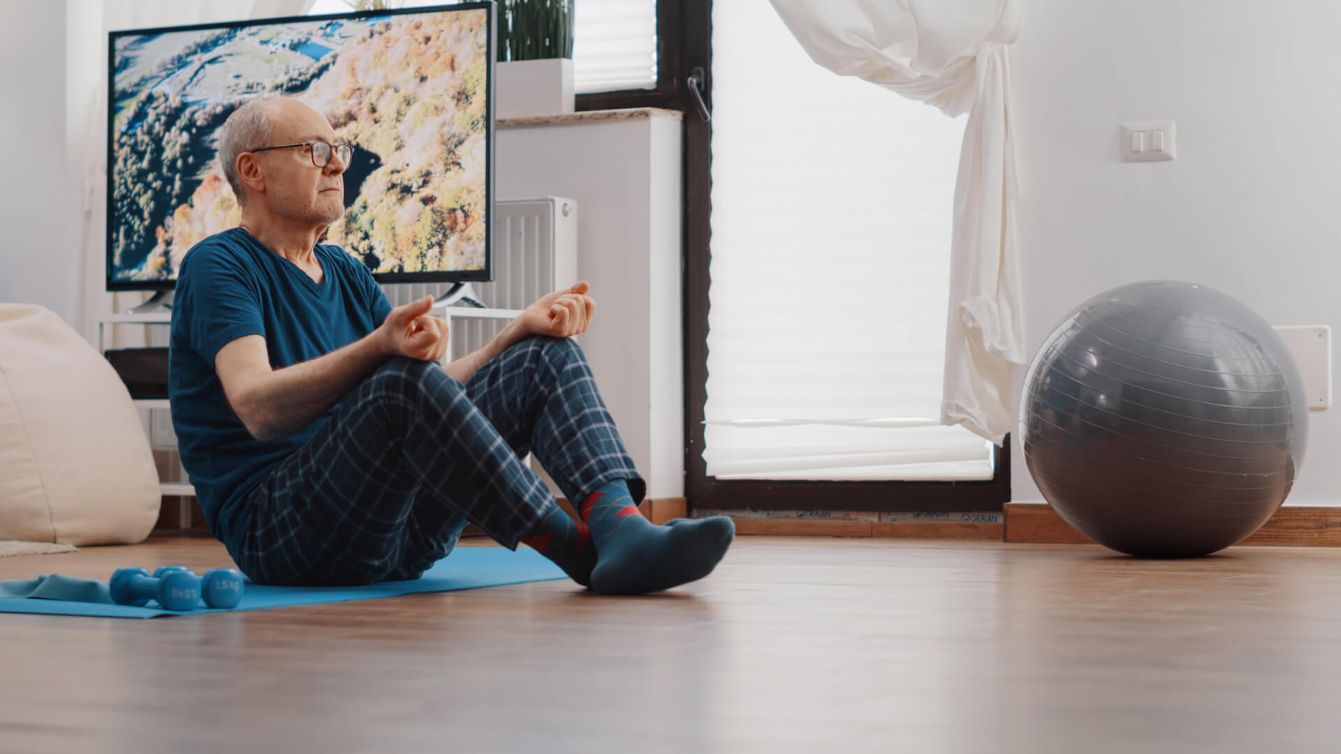 Una persona anciana realiza ejercicios de pilates en el salón de su comedor, mientras se encuentra sentado para reducir la presencia de sibilancias mientras duerme, contrarrestándolo con ejercicio físico moderado. 
