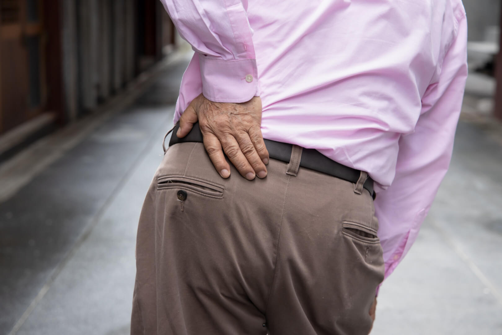 Un hombre anciano se toca la zona lumbar ante las molestias. La polimialgia reumática afecta a personas mayores y una de las zonas más comunes es la zona lumbar.