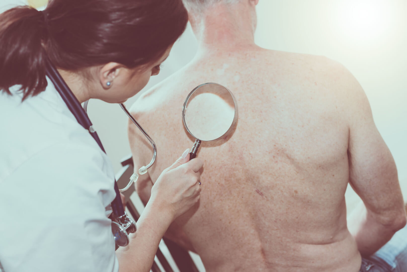 Una doctora ausculta la espalda de un anciano ante un posible caso de alergia primaveral en la piel.