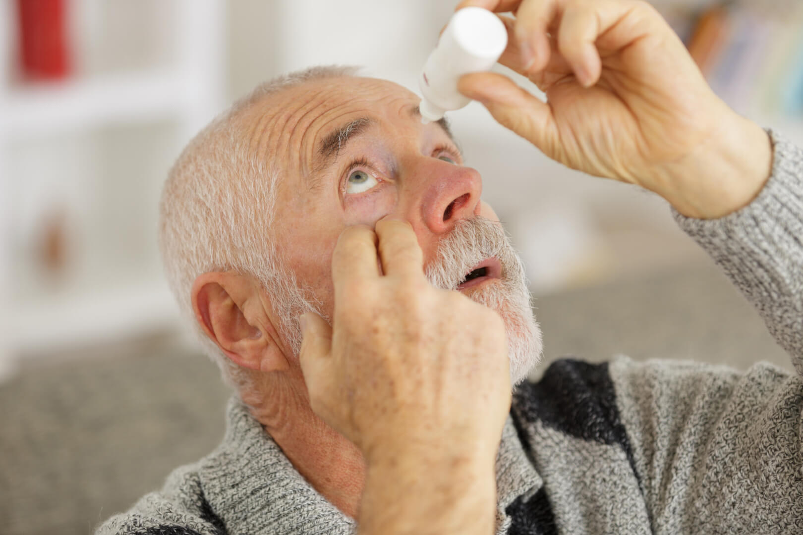 Un señor de edad avanzada se deposita gotas ojos alergia primavera