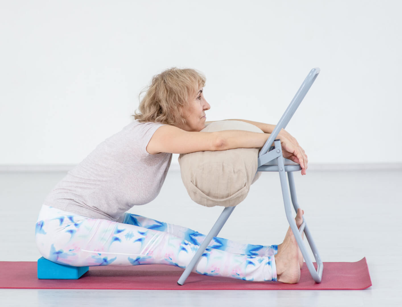 Una mujer mayor se sirve de una silla para practicar yoga.