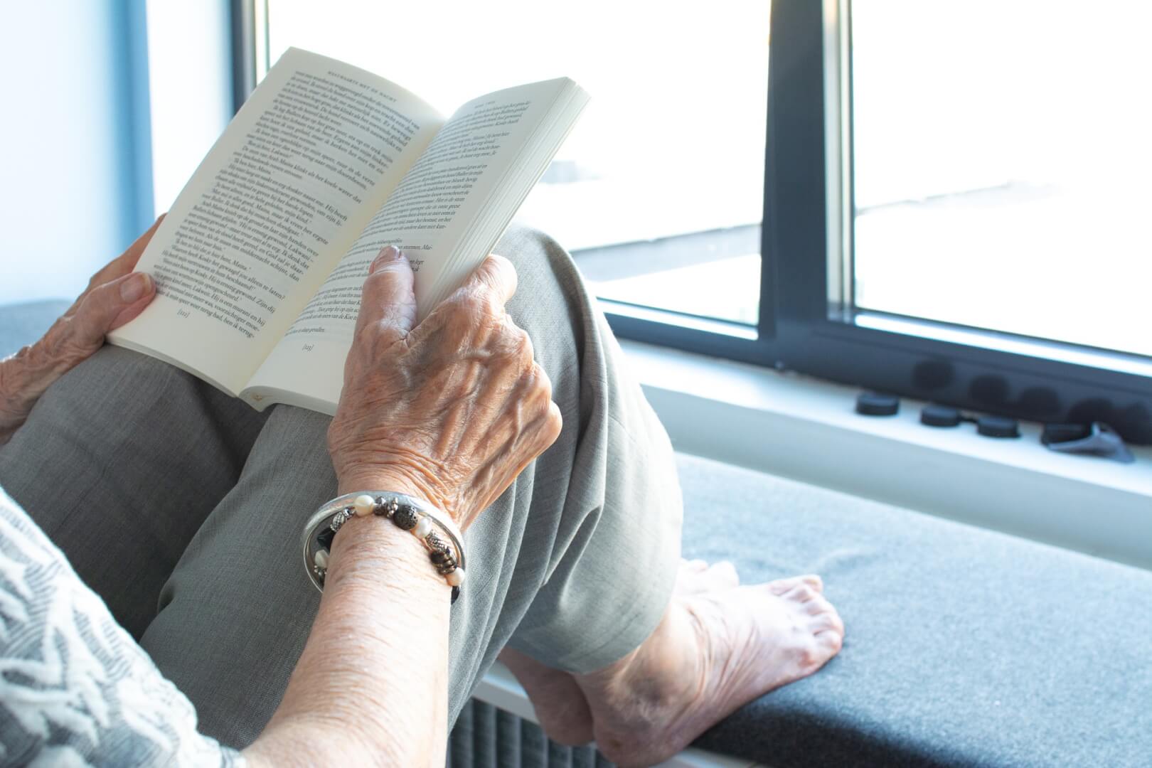Unas manos de una mujer de edad avanzada leyendo un libro en inglés. 