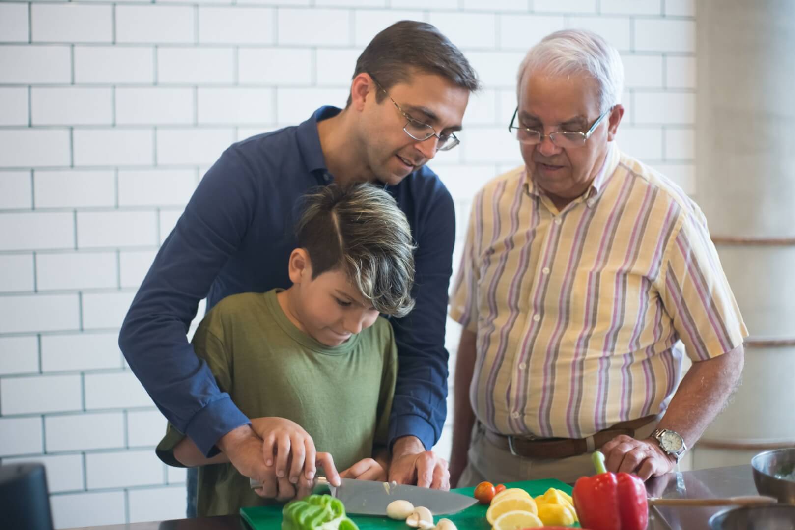 Un nieto, su padre y su abuelo preparando un almuerzo por el Día del Padre. 