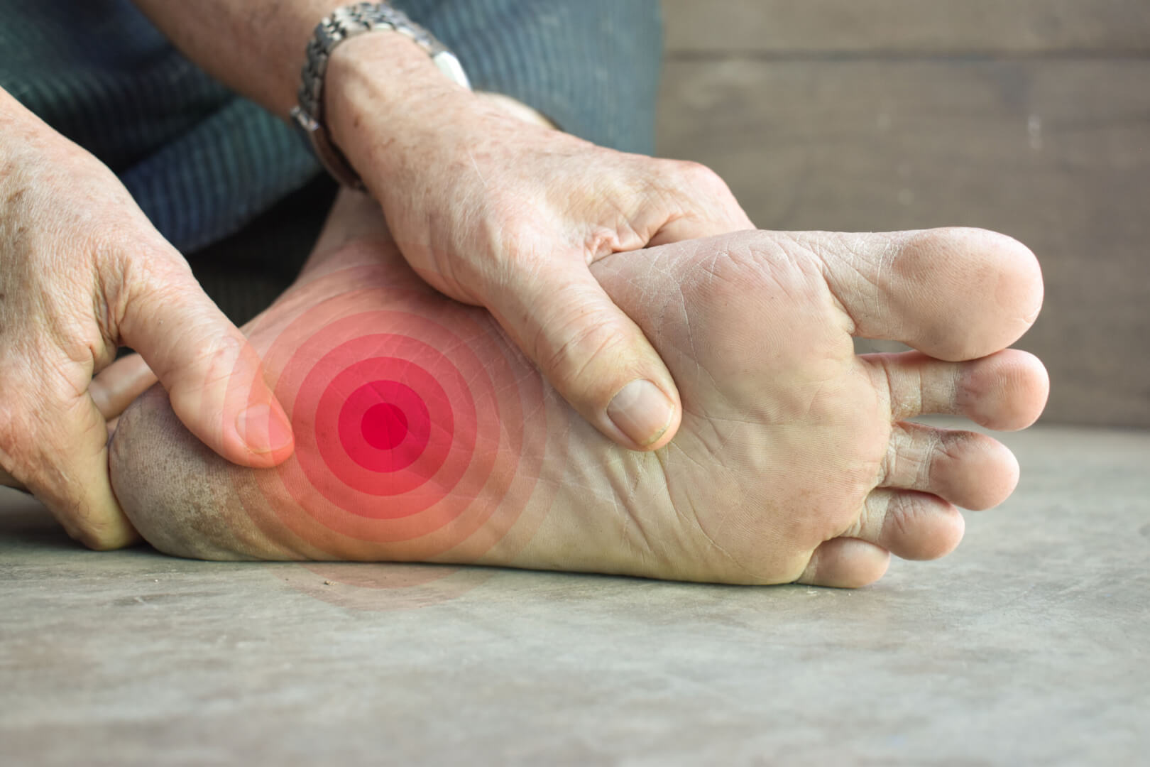 Una persona mayor se masajea el pie izquierdo al notar un hormigueo o adormecimiento por parestesia.