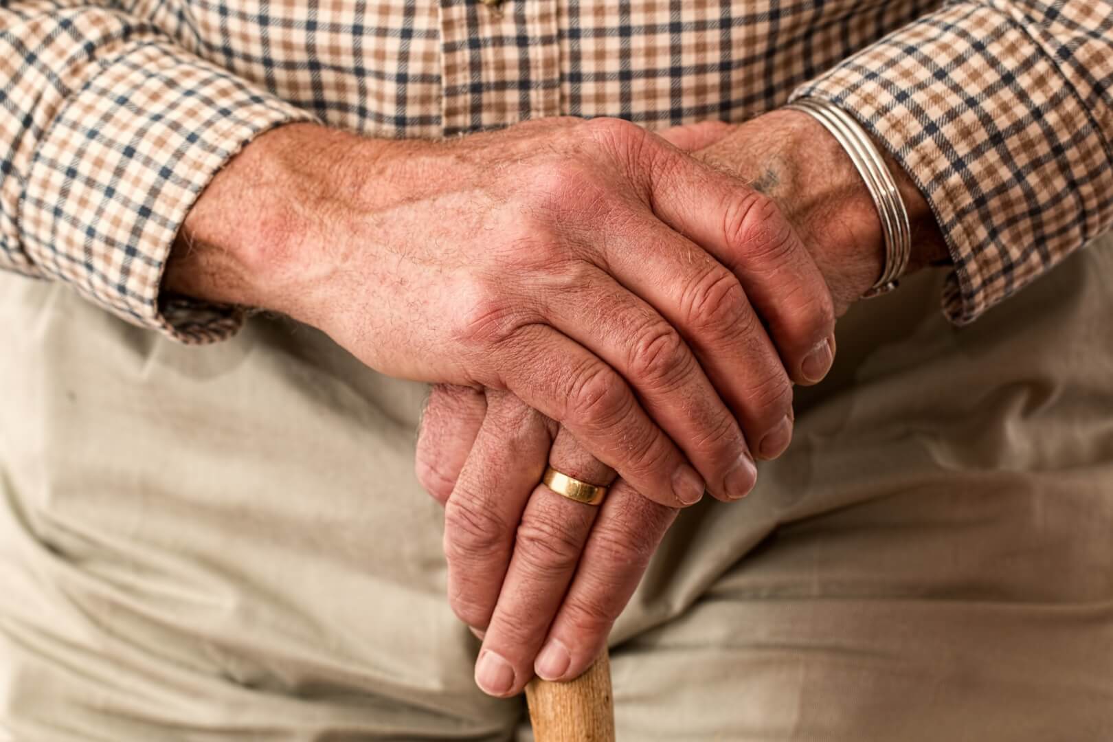 Un anciano se toca una mano con la otra ante el adormecimiento de la mano por parestesia.