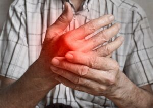 Una persona tomándose la mano, con una zona en rojo indicando dolor