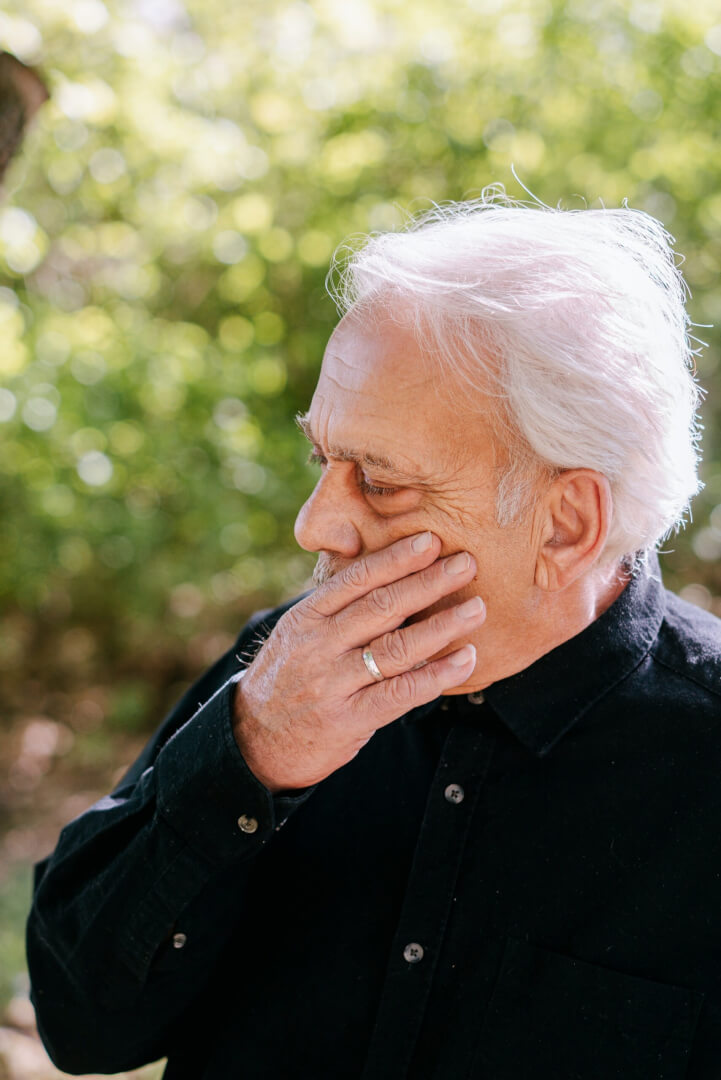 Un hombre mayor se toca el pómulo de la cara ante el adormecimiento de esa zona por sufrir parestesia. 
