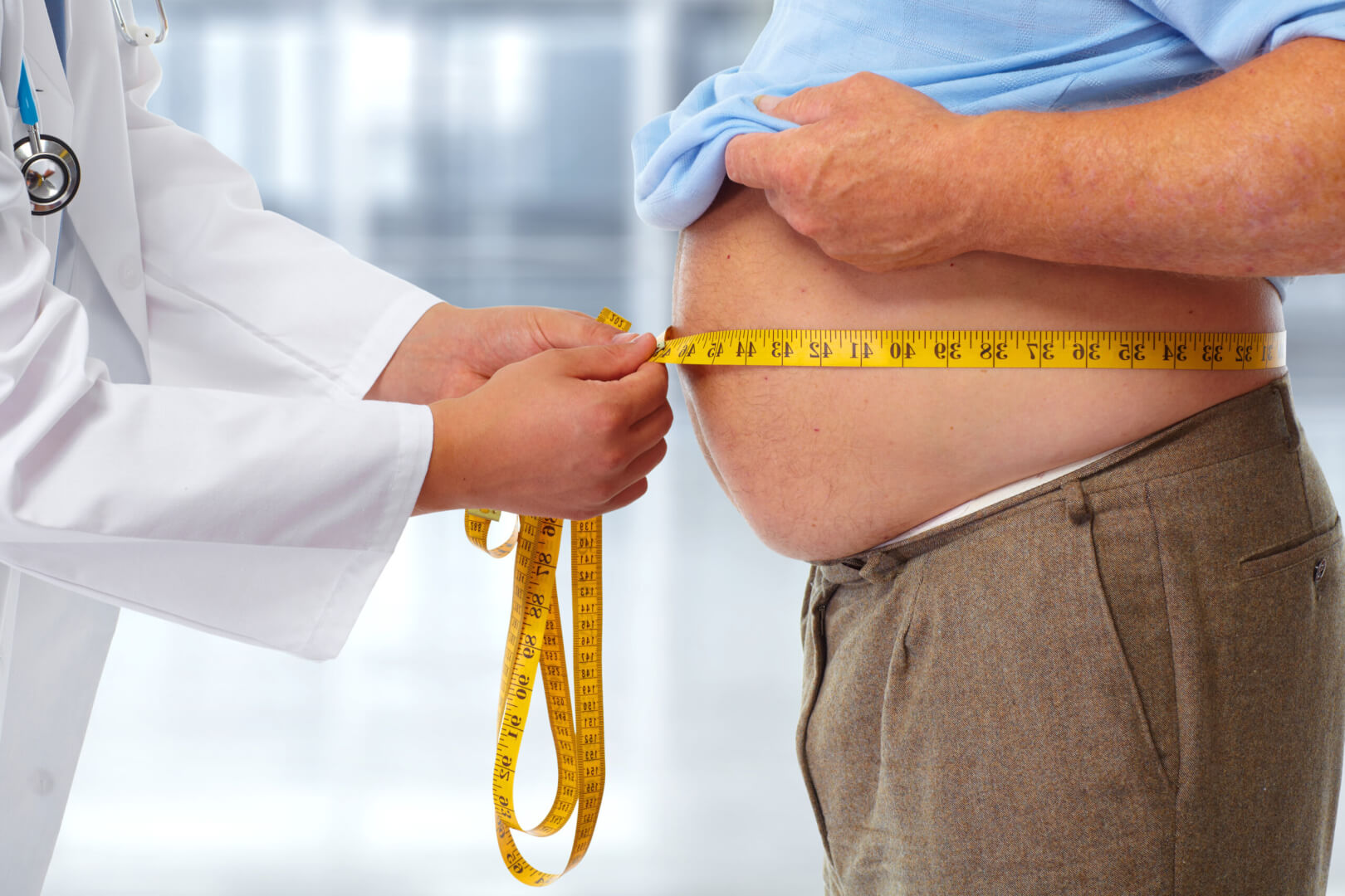 Un médico mide la cintura y el peso de una persona mayor para detectar problemas de salud posibles. 