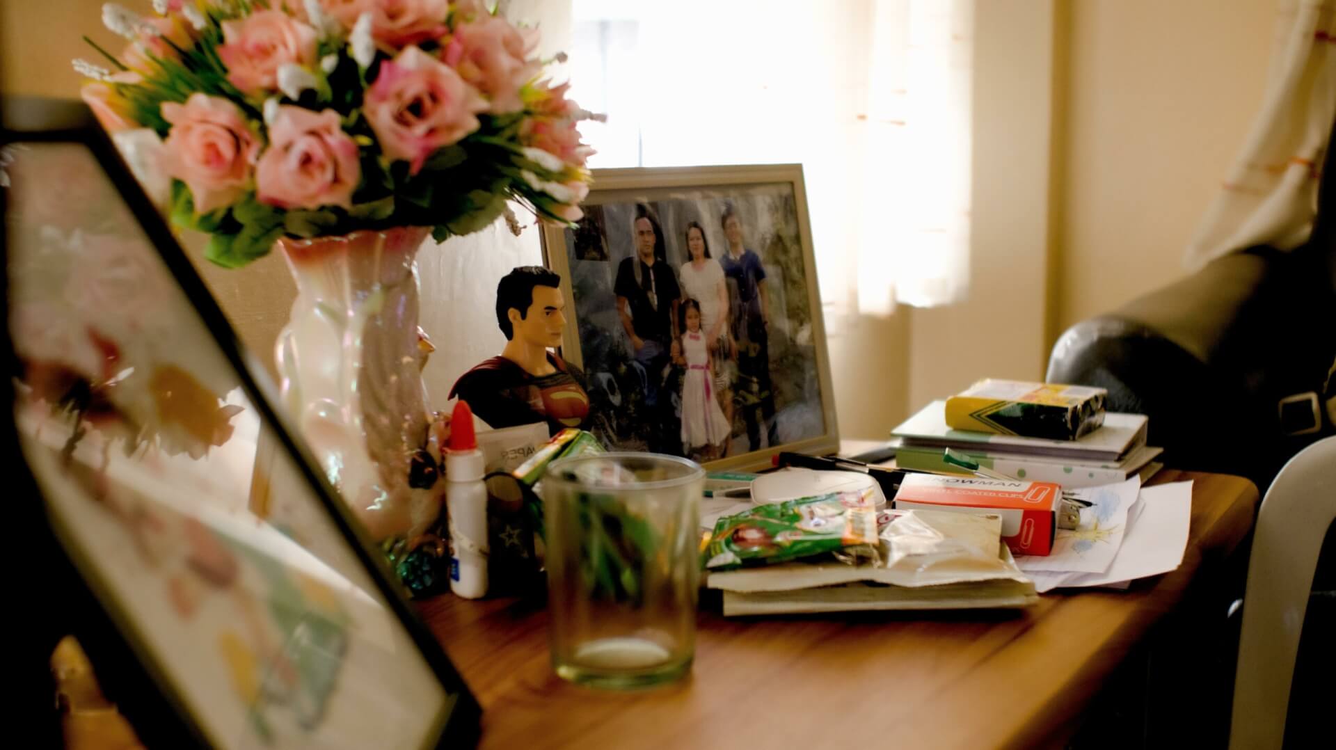 Un marco de foto familiar situado sobre una mesita en una habitación junto a unas flores. 