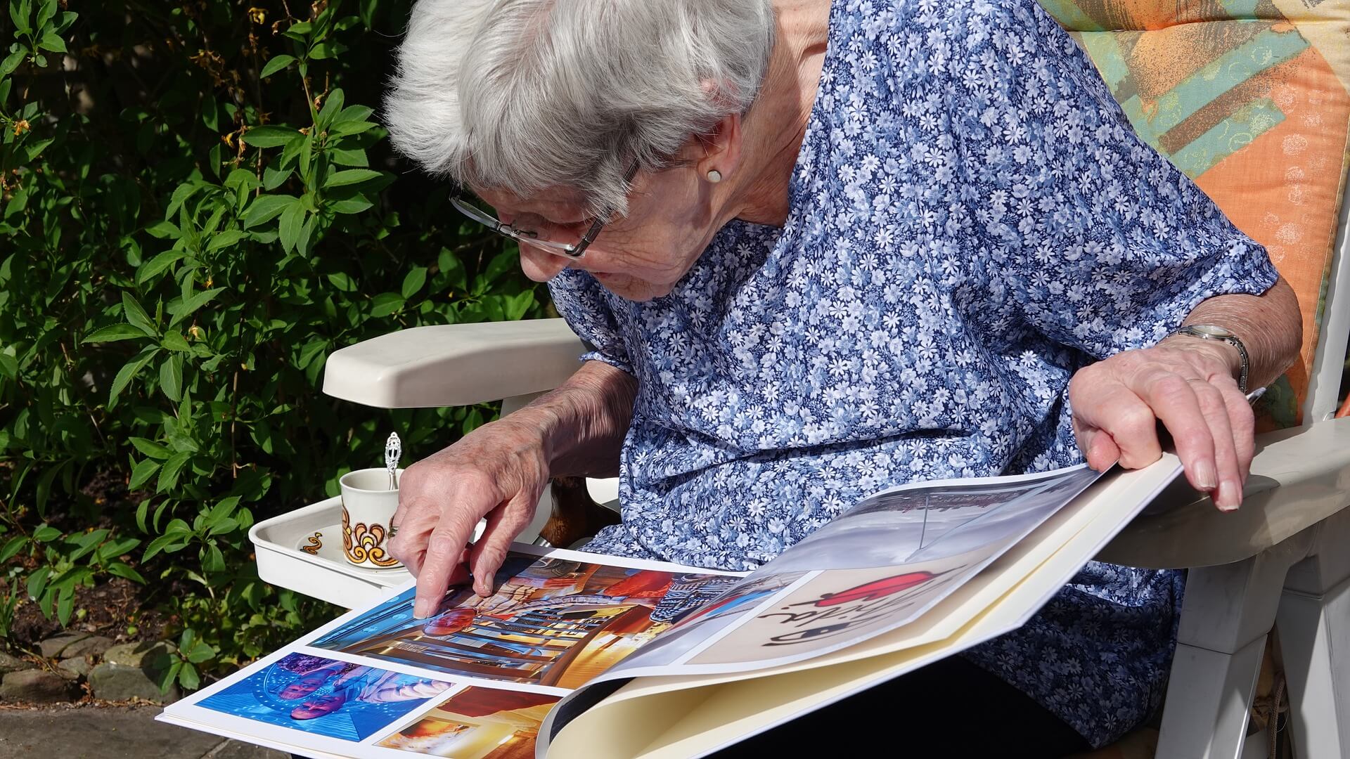 Una mujer mayor observa detenidamente un álbum de fotos para recordar momentos de su pasado.