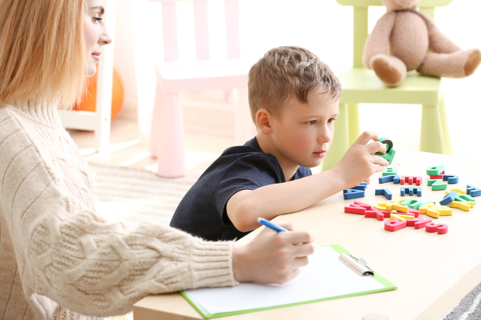 Un niño autista juega con un puzzle con su madre en casa. 
