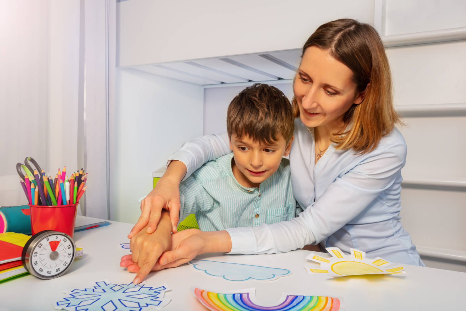 Una madre juega y enseña a su hijo autista a reconocer objetos sobre una mesa. 