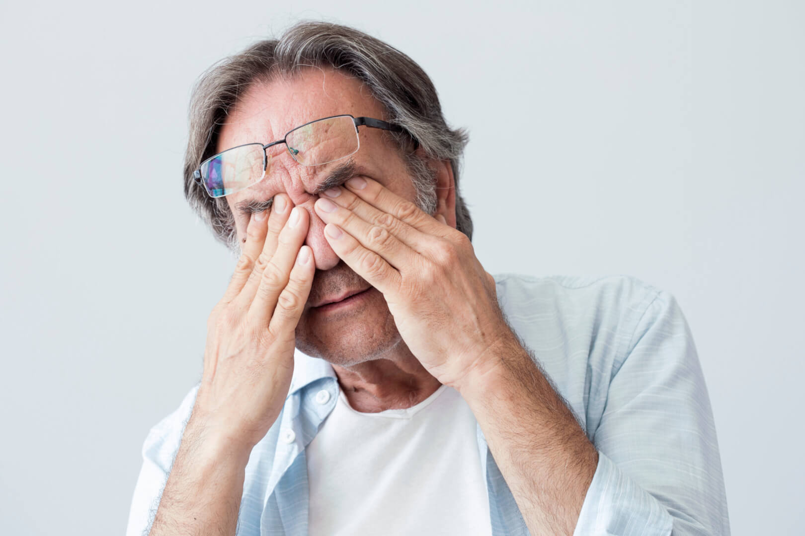 Un hombre mayor se frota los ojos como señal de fatiga