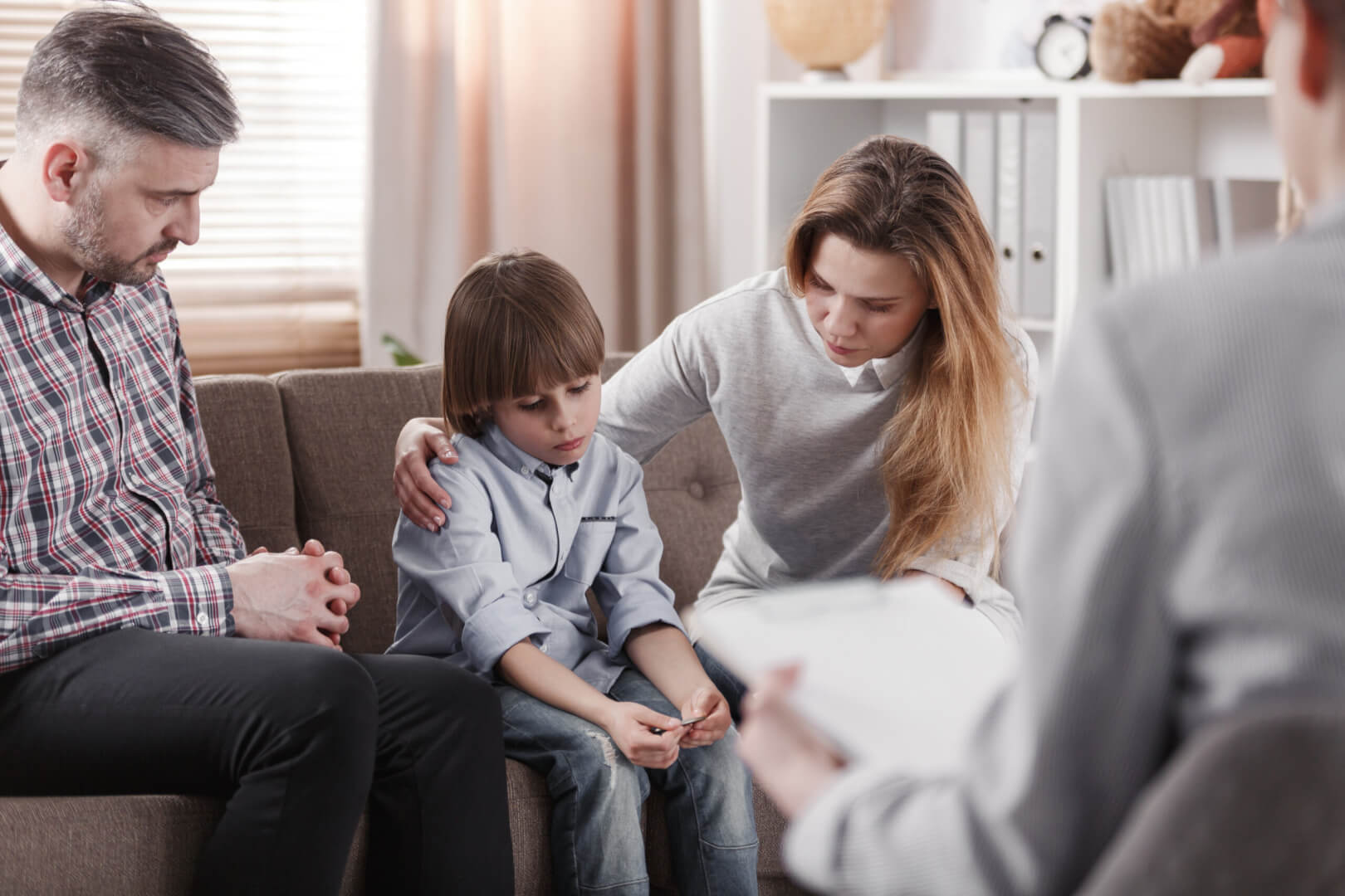 Una familia con un padre, una madre y un hijo con un psicólogo en una terapia para superar la pérdida de un familiar. 