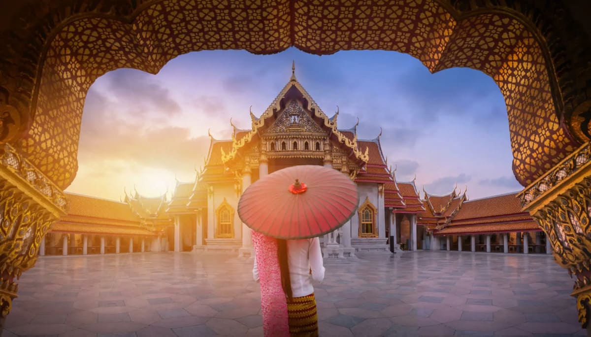 Una persona de espaldas con un paraguas en un templo de Tailandia